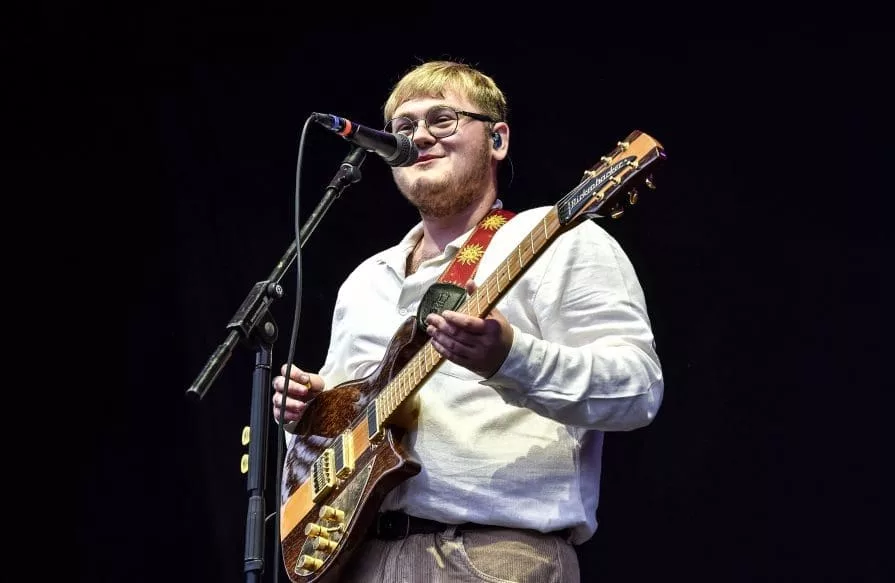 man with glasses and guitar on stage