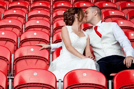 bride and groom kissing on red chairs at the BrewDog Stadium's wedding venue in St Helens