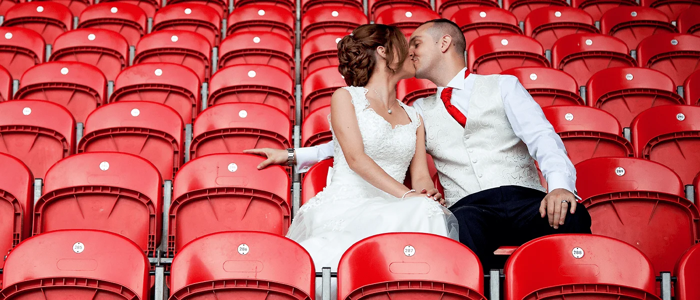 bride and groom kissing on red chairs at the BrewDog Stadium's wedding venue in St Helens